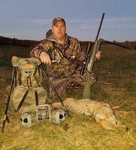 Hunter kneeling next to a dead coyote