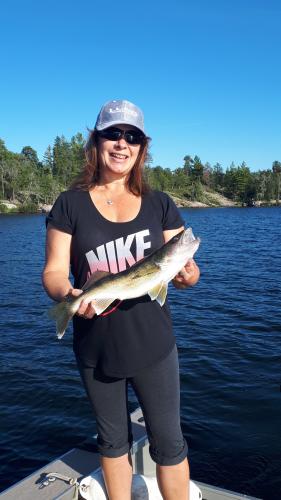 Lady angler holding Walleye catch in a boat on a lake