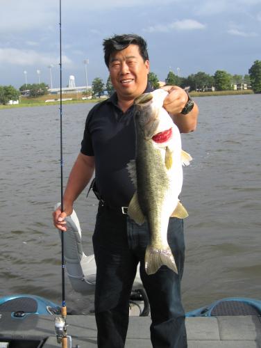 Angler standing near waters edge with Largemouth Bass