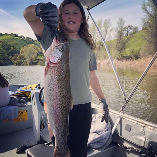 Young Gwendolyn standing in a boatholding a large salmon fish