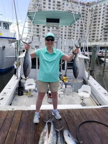 Lady angler holding up two of may blackfin tuna she caught
