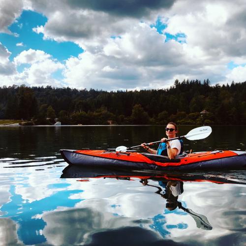 Woman kayaking on a calm lake where the water is like glass