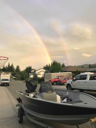 Boat parked on a street with a double rainbow in the sky