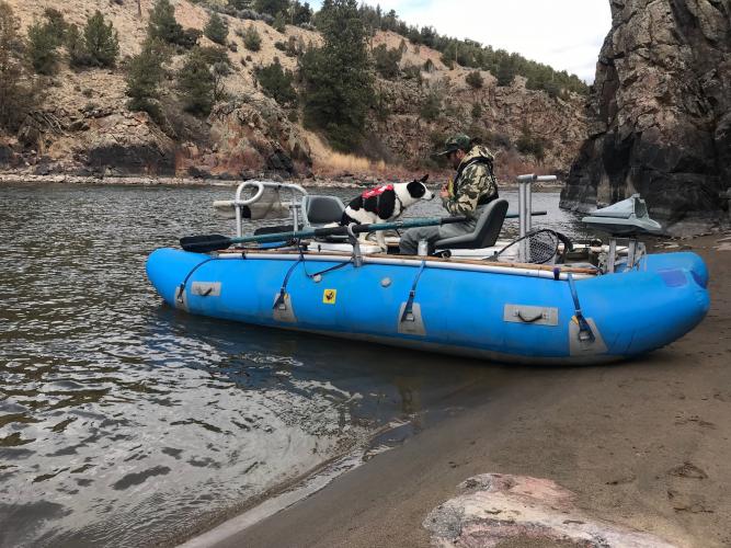 Soft sided tube boat rigged for a fishing float with angler and dog aboard