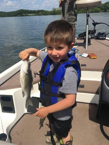Young boy on bass boat holding a bass