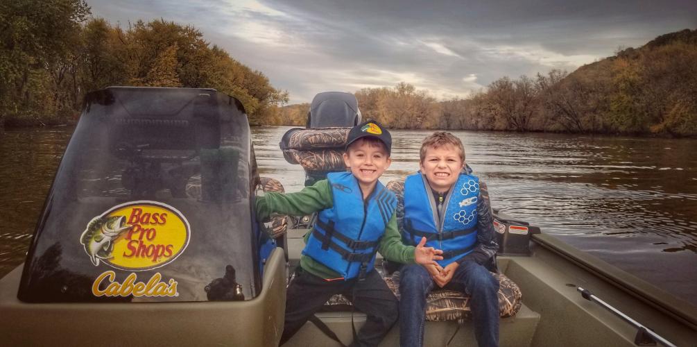 Two young boys sitting in a Tracker jon boat
