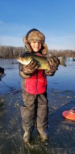 Boy ice angler with a largemouth bass