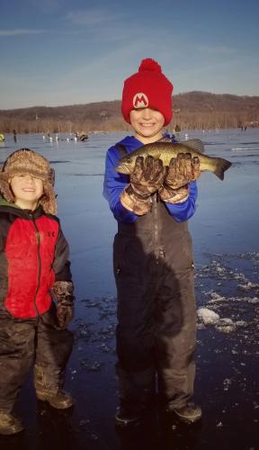 Young ice anger standing next to his younger brother holding a walleye