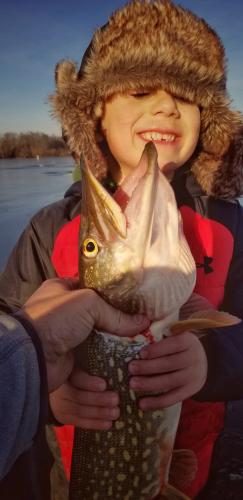 Young ice angler holding a norther pike