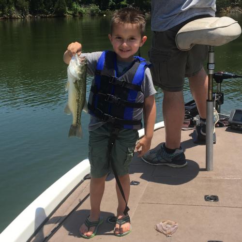 Boy angler on bass boat holding largemouth bass