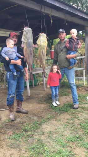 Two fathers with three children and two large catfish
