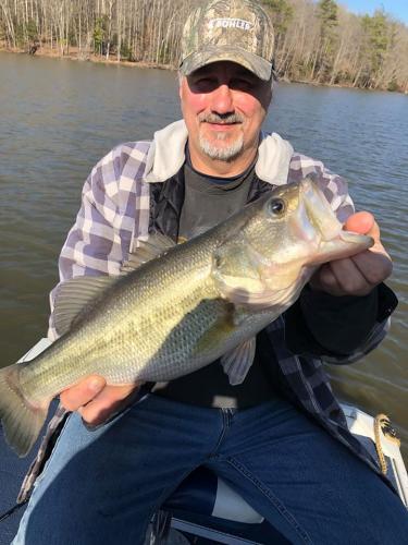 Bass angler sitting on the lake holding a large bass