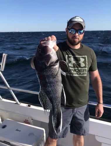 Saltwater angler on the sea hold a sea bass