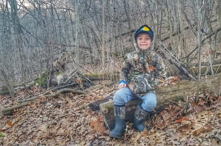Young boy in a forest wearing camo