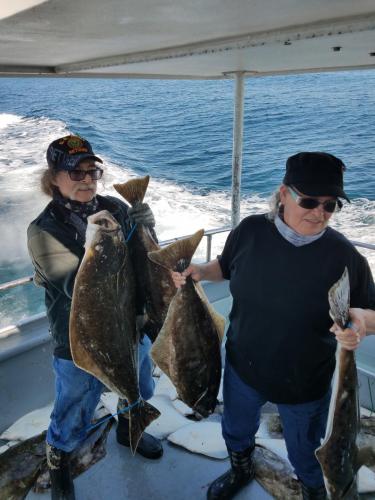 Two people holding several flounder