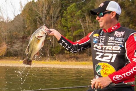 Kevin VanDam during fishing tournament holding up a bass