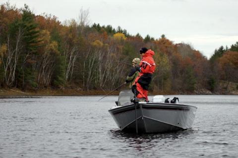 Angler fishing for bass from a boat in cold weather 