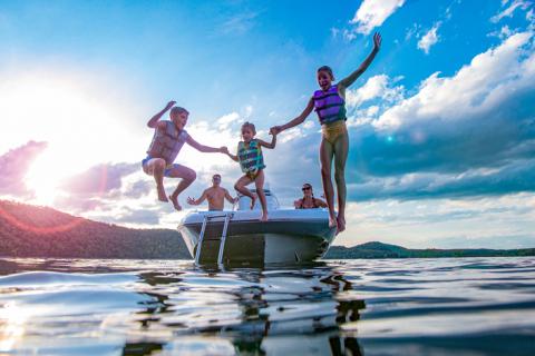 Family of boaters jumps from boat into a lake