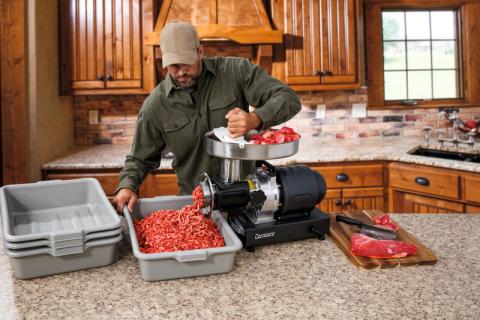 Man using Cabela's Carnivore meat grinder to grind meat