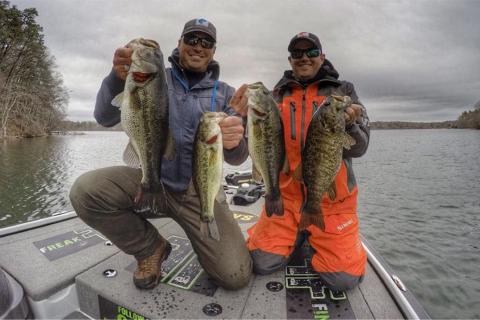 Two anglers fall fishing are holding up their catch of two large bass each