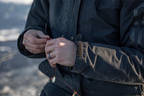 Ice fishing angler rigging his fishing line and hook