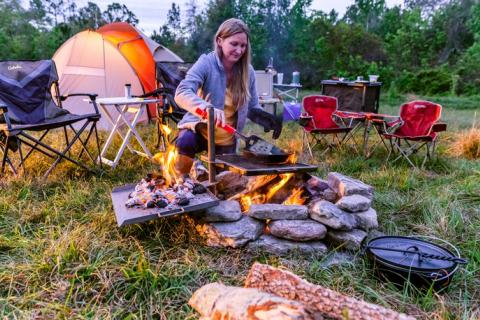 Women cooking next to her camp chair