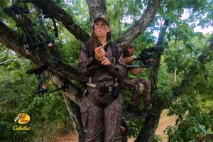 Lady bow hunter in a tree in a treestand preparing for the hunt