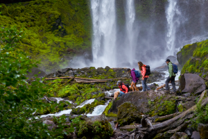 Four hikers in Ascend Bone-Dry rain gear hiking with waterfall in background
