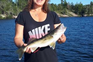 Lady angler holding Walleye catch in a boat on a lake