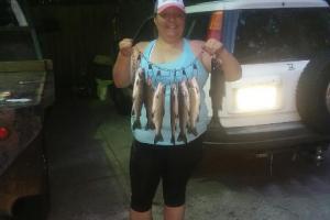 Lady angler in a parking lot hold up a stringer of trout