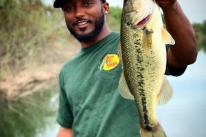 Happy angler with Bass Pro Shops hat is holding up a nice largemouth pass