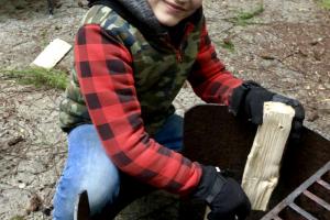 Young camper is building a camp fire