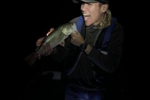 Angler playfully holding his bass with his mouth wide open matching the fishes large mouth