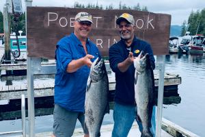 Two anglers show off their Chinook Salmon on a boat dock