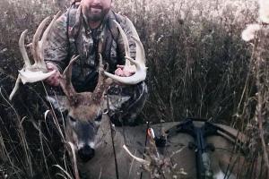 Bow hunter in field with a large buck he shot
