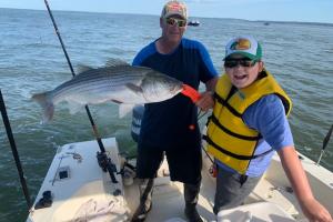 Family fishng striped bass is proud of this nice catch
