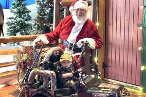 Toddler in toy jeep getting hisphoto with Santa at Bass Pro