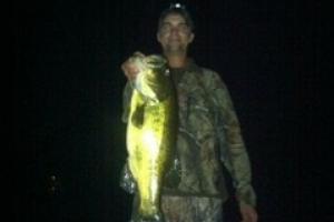 Angler dressed in camo holding a large bass 