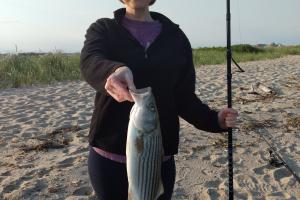 Lady angerl on a beach with stripe bass