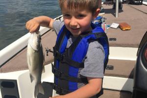 Young boy on bass boat holding a bass