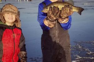 Young ice anger standing next to his younger brother holding a walleye