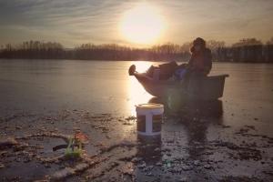 Young angler on frozen lake ice fishing