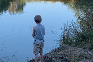 Young boy standing on the bank fishing