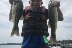 Boy angler holding two bass fish