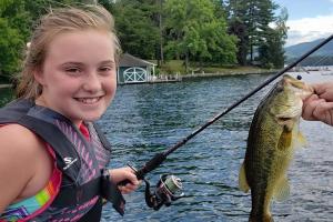 Girl holding a fishing rod and reel with a nice sized bass