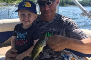 Father & son on a pontoon hold a bass