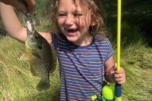 Young girl smilling at the bluegill fish she caught