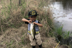 Boy angler in a batman hat catches the fish