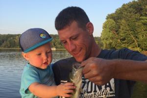 Father holding fish for his young child to touch