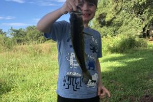 Boy angler holding up a bass by its lip